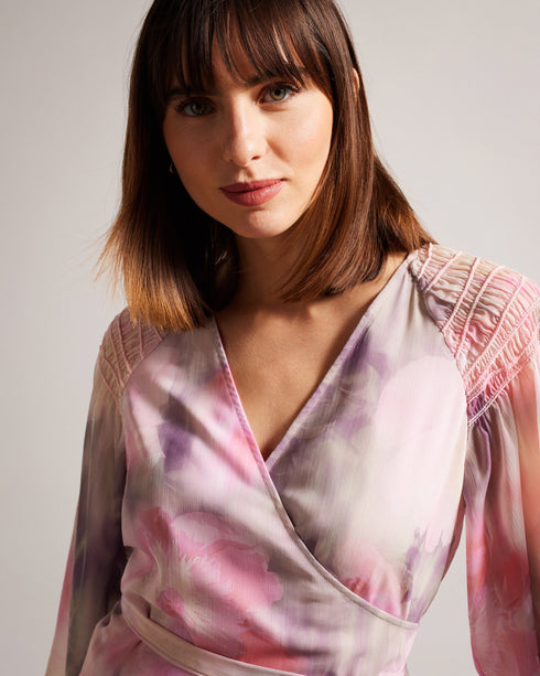 EMILIAH-Tops-Add some spring florals to your wardrobe with our EMILIAH blouse, which features a wrap front and blouson sleeves. Smocked shoulders give the piece extra texture without the bulk.The fabric of this product is made with 100% recycled polyester. Using recycled polyester helps divert plastic waste from ending in landfills, and helps us to reduce our dependence on virgin materials. Blouse Wrap front Blouson sleeves Smocked shoulders Blurred floral print Self tie waist V-neck Julia is 5'10" / 1.78m